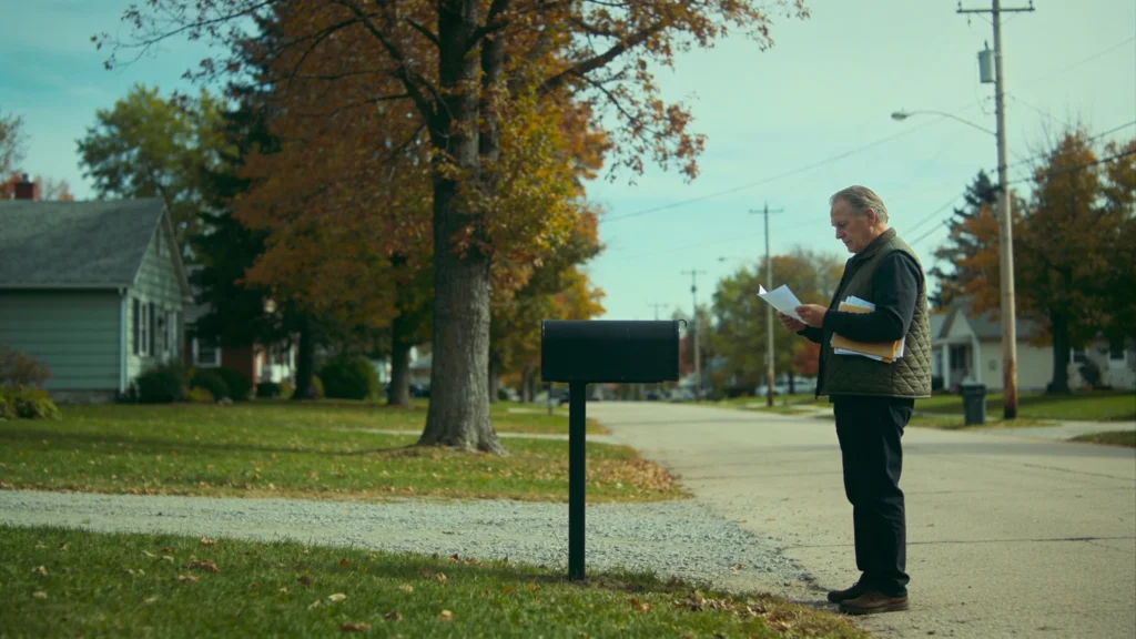 A man of about sixty-five reads a letter at the end of his driveway, the mail that starts arriving as Medicare nears.
